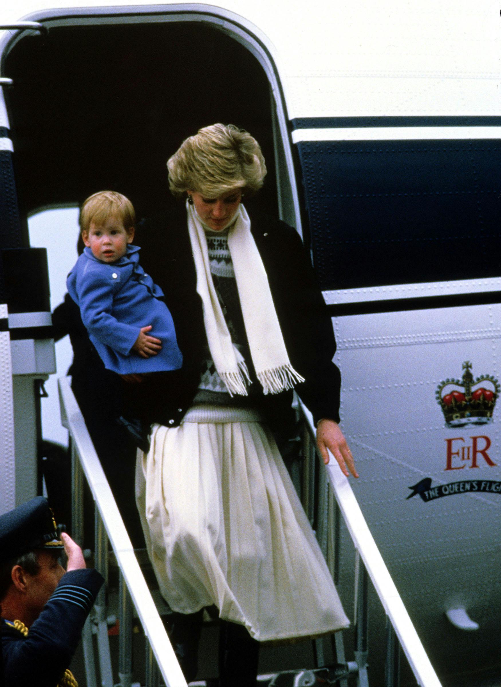 Prins Harry bliver båret ned ad trapperne fra flyvet. 