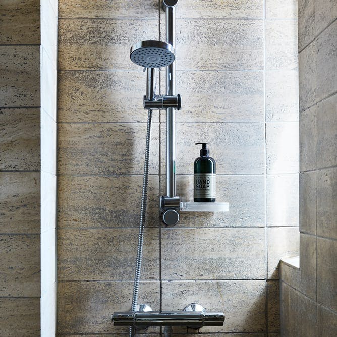 Badeværelse med brune og grå fliser i brusekabinen.