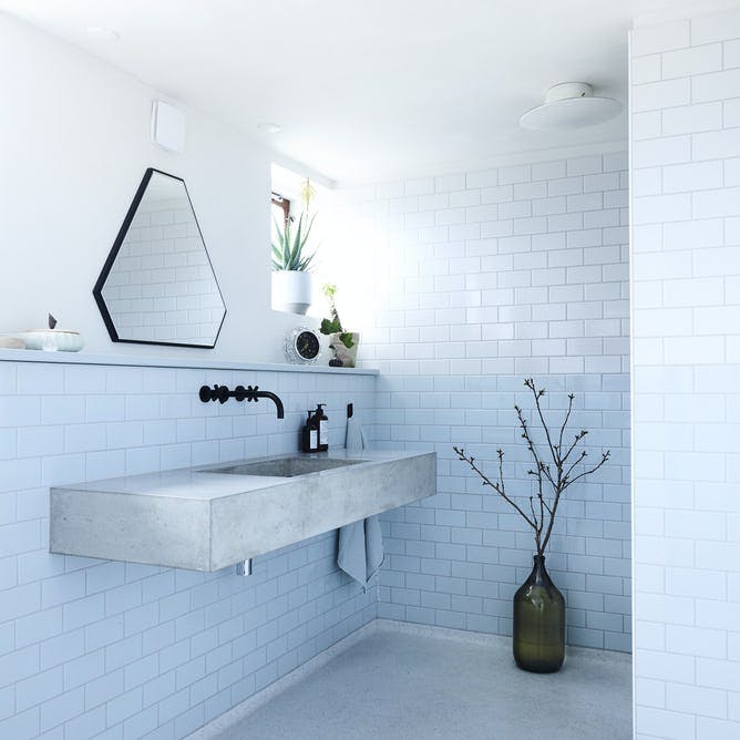 Badeværelse med blå fliser og stor håndvask.