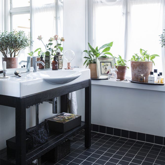 Badeværelse med sorte fliser og håndvask på ben.