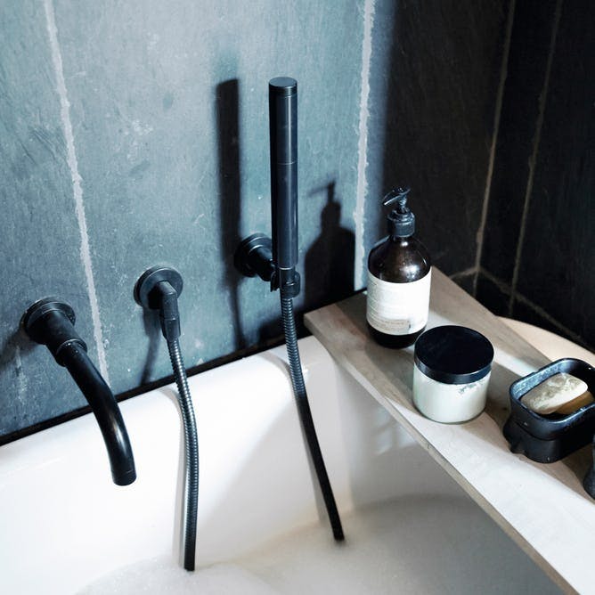 Badeværelse: Sort armatur på badekarret.