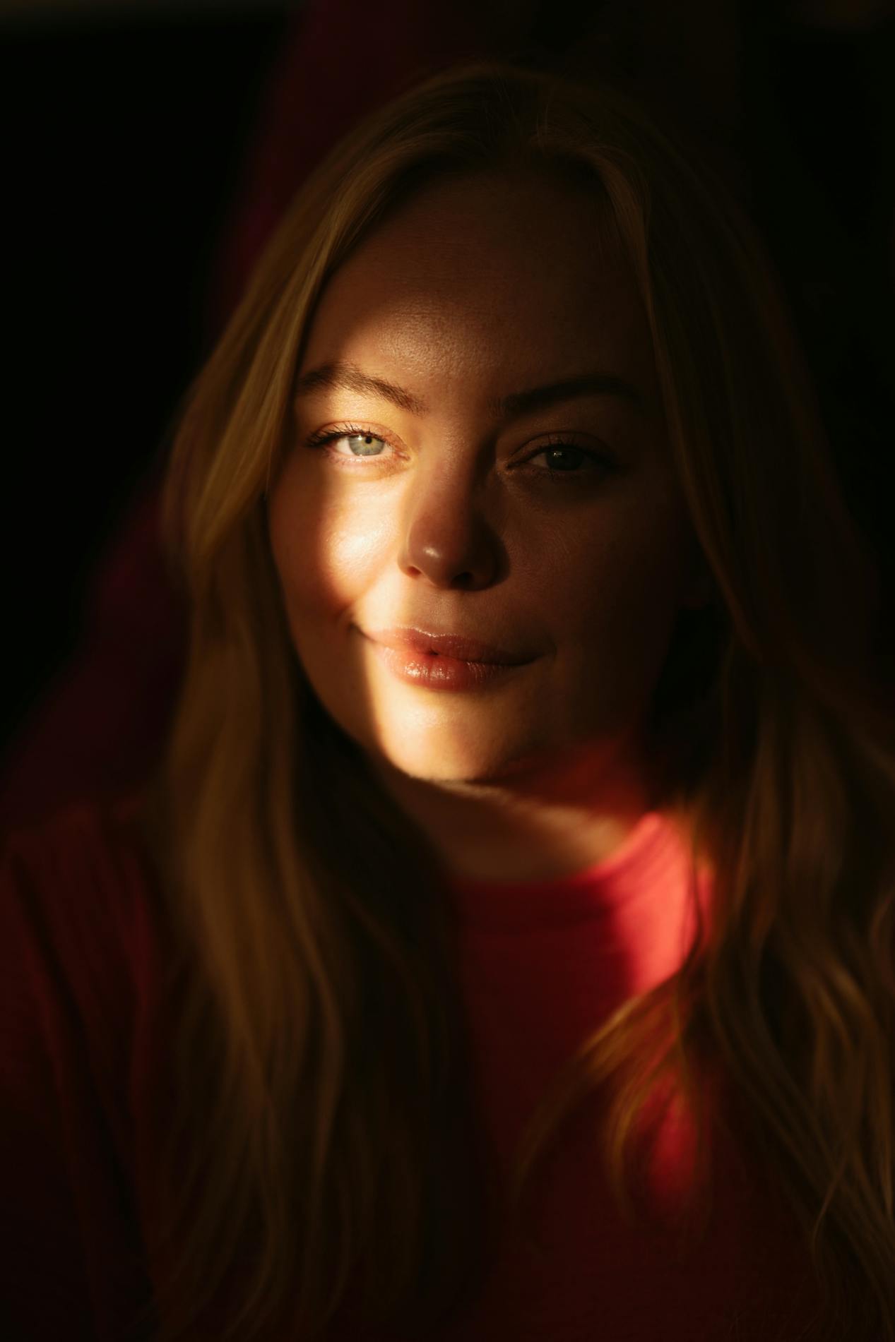 Maria Gudme fotograferet tæt på i et mørkt rum. Hendes ansigt er mest henlagt i mørke, men en lysstribe går ned gennem