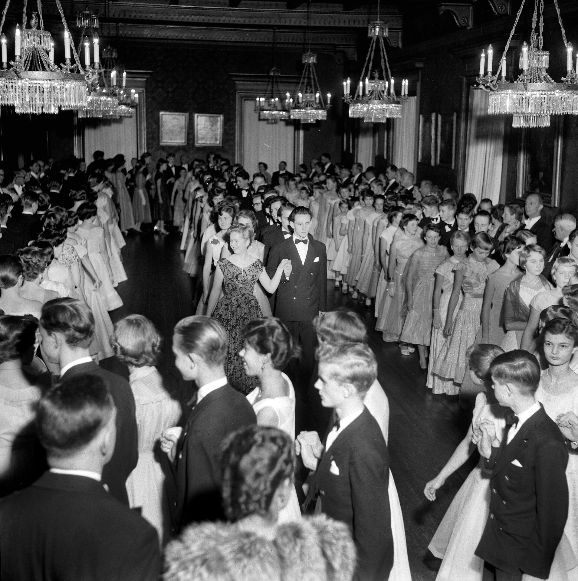 Herlufsholm Skoles"diple"med inviterede"dansemus"marcherer ind i skolens festsal til Trollebal lørdag den 14. januar 1956. Den dag hyldes skolens stiftere, admiral Herluf Trolle og hans hustru, Birgitte Gøye.
