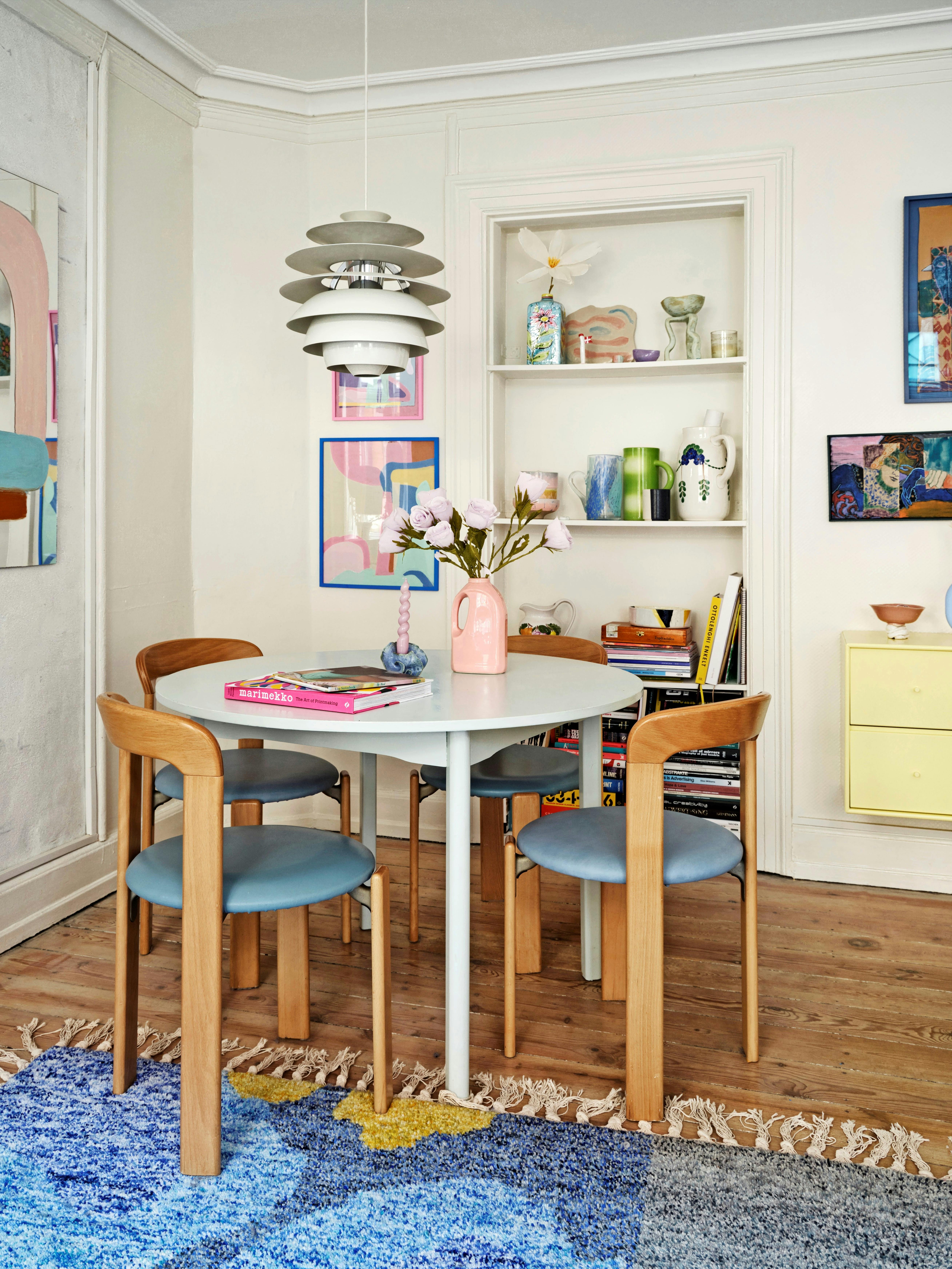 Et rundt spisebord er pladsoptimerende i den lille lejlighed. Spisebordet her er købt brugt, omkring det står stolene Rey Chair af Bruno Rey, og fra loftet hænger PH-lampen Snowball. Gulvtæppet er fra Nordic Knots x Tableau.