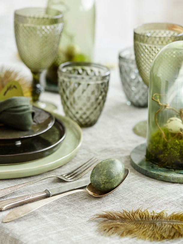 Påskefrokostbord pyntet med påskeæg og stel i grønne nuancer