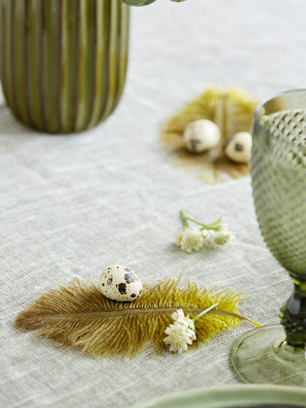 Fjer og påskeæg der pynter på påskebordet