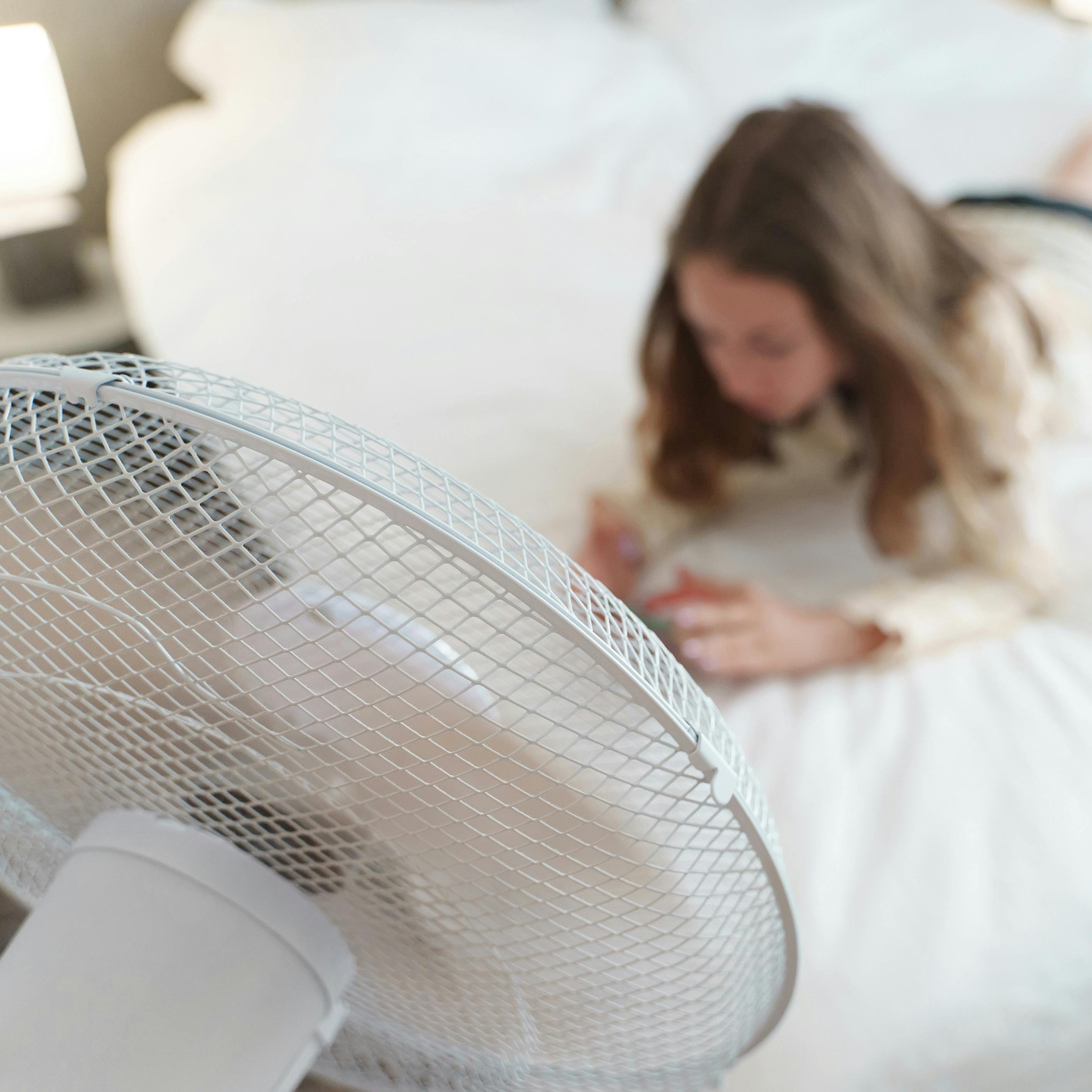 Teenager lies with the phone in front of cooling fan.