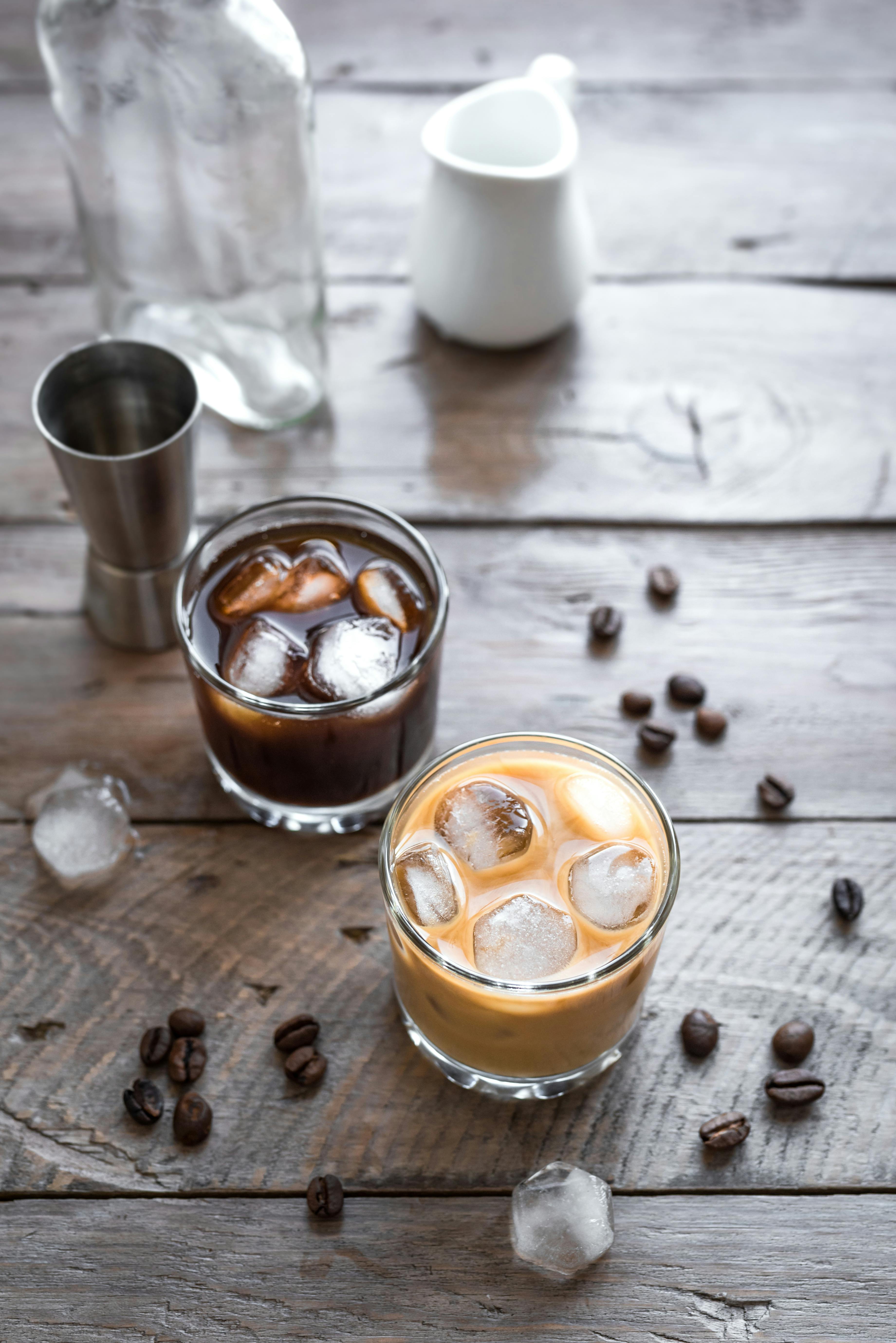 Black and White Russian Cocktails with Vodka, Coffee Liquor and Cream. Homemade iced Alcohol Boozy Black Russian and White Russian drink with coffee beans on wooden background, copy space.