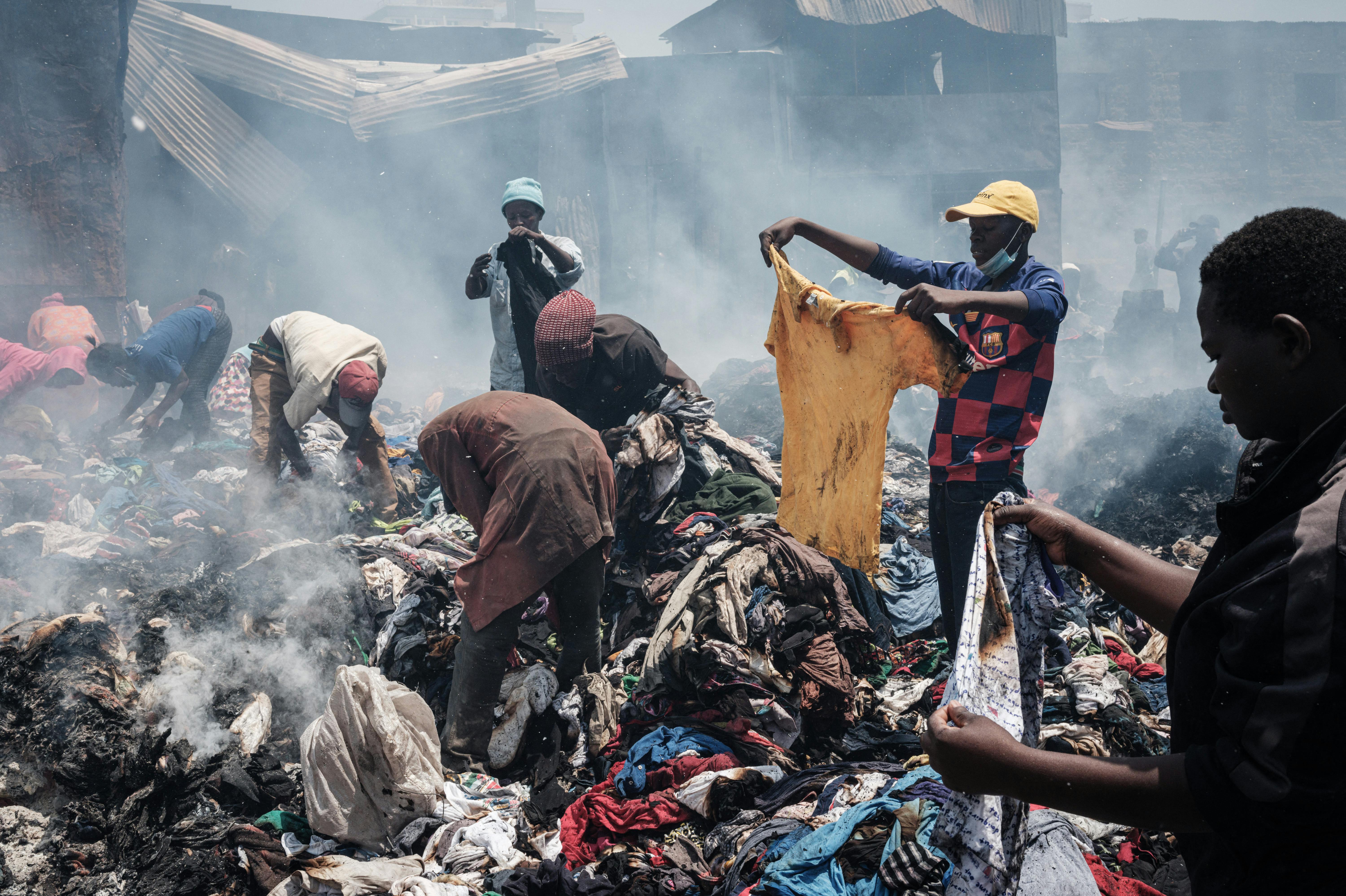 Traders scavenge clothes from debris burnt down by the fire in the early morning at Gikomba market, East Africa's largest second hand clothing market, in Nairobi, Kenya, on November 8, 2021. A court has ordered a part of the market to be evicted to build a health centre but many traders are against the decision, according to residents. Yasuyoshi CHIBA / AFP