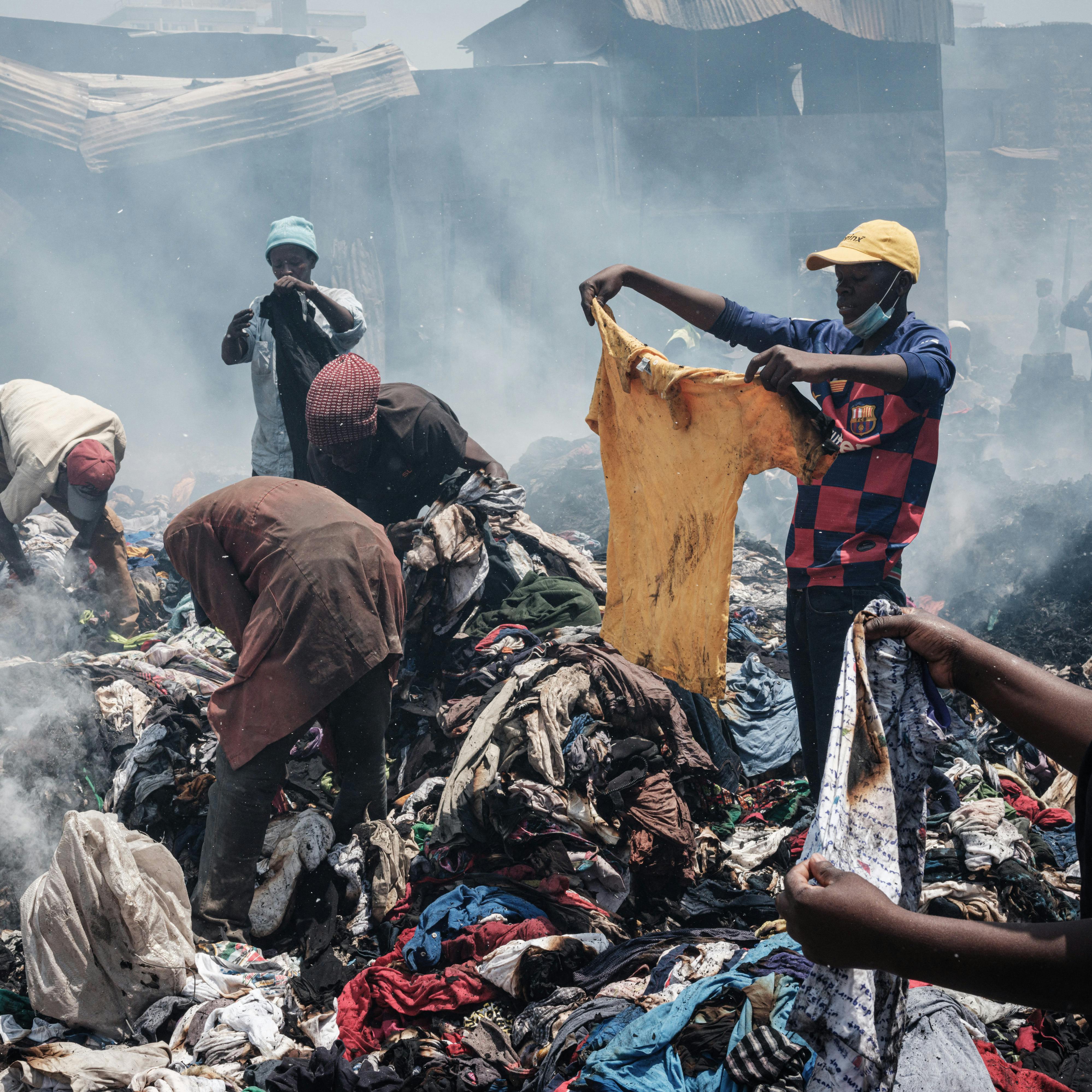 Traders scavenge clothes from debris burnt down by the fire in the early morning at Gikomba market, East Africa's largest second hand clothing market, in Nairobi, Kenya, on November 8, 2021. A court has ordered a part of the market to be evicted to build a health centre but many traders are against the decision, according to residents. Yasuyoshi CHIBA / AFP