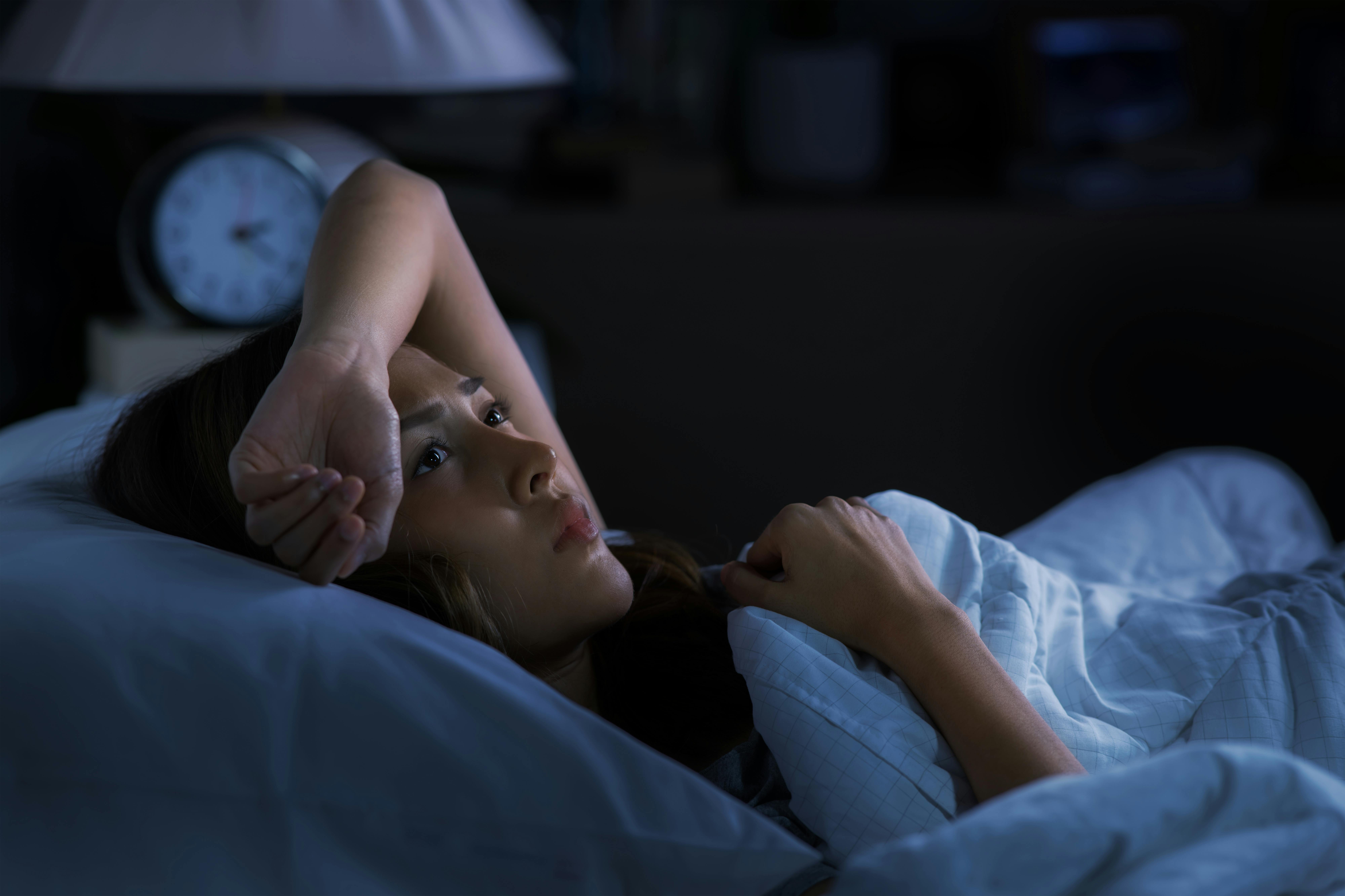 Depressed young woman lying in bed cannot sleep from insomnia