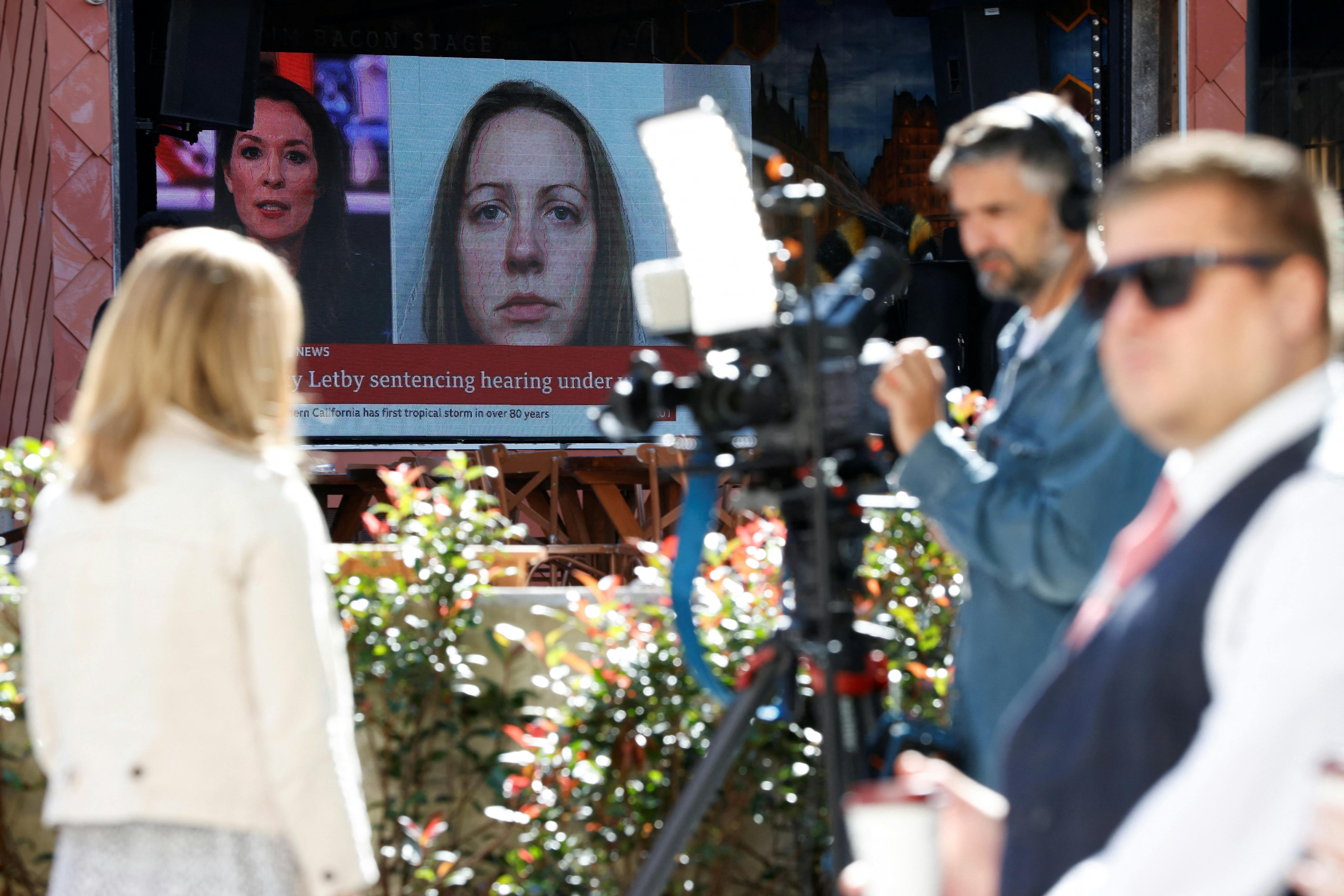 Members of the media work near a large screen showing a picture of convicted hospital nurse Lucy Letby, ahead of her sentencing, outside the Manchester Crown Court, in Manchester, Britain, August 21, 2023. REUTERS/Phil Noble