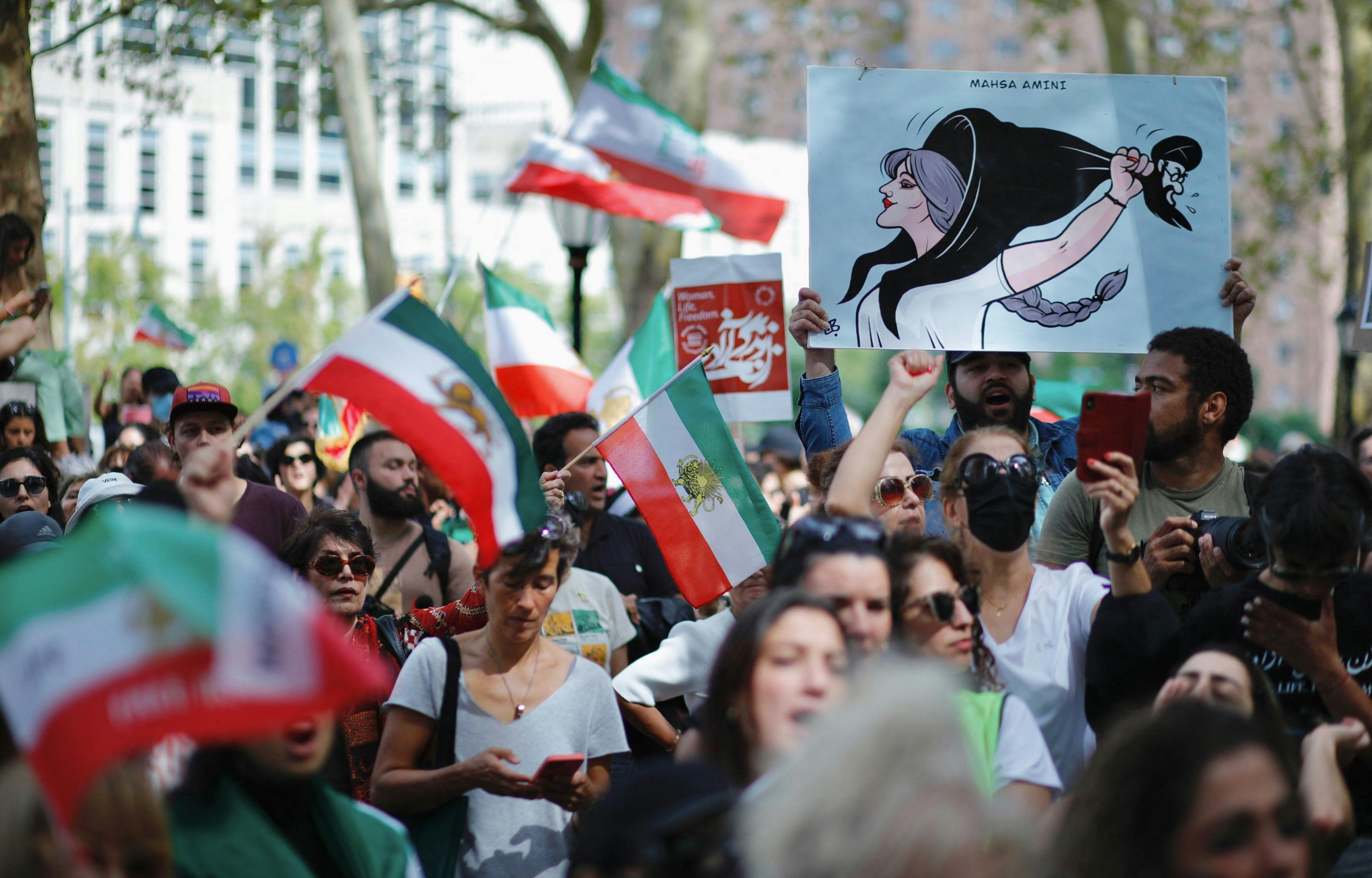 TOPSHOT - People hold placards and wave Iranian flags during a global protest in solidarity with Iranian women in New York on September 16, 2023, on the first anniversary of the death of Iranian Kurd Mahsa Amini in custody. (Photo by Kena Betancur / AFP)