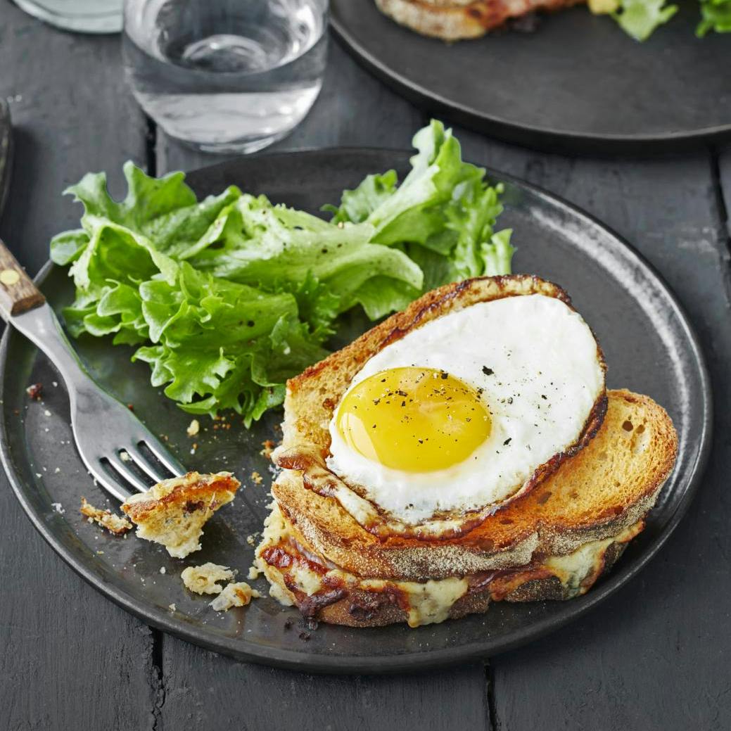 Croque-madame med spejlæg og grønt - på gråligt service. 