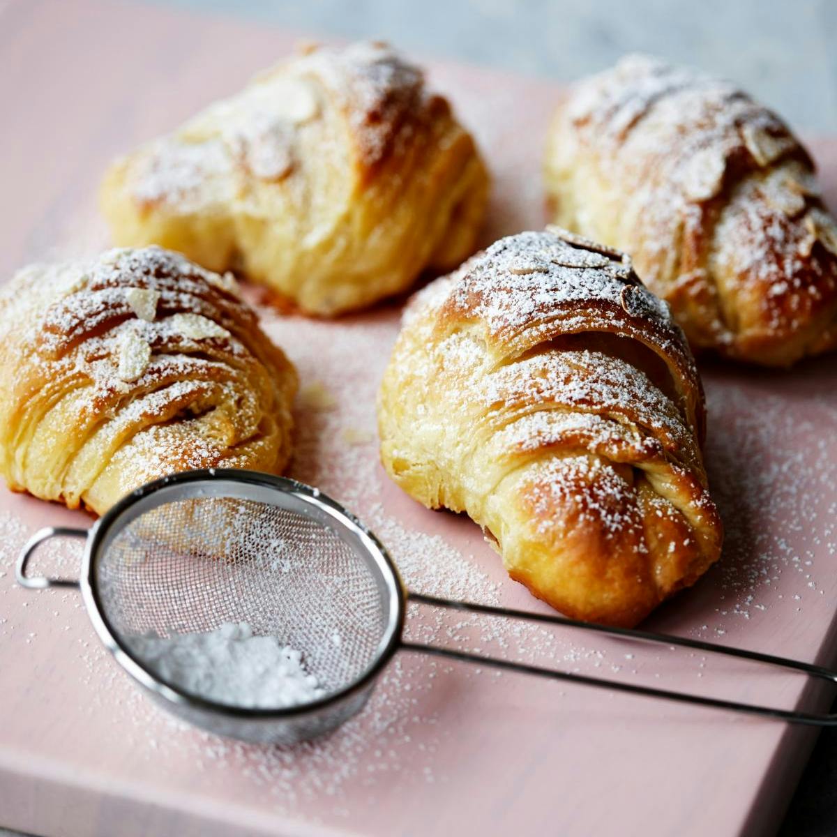 Hjemmelavede croissanter med drys af flormelis og mandelflager