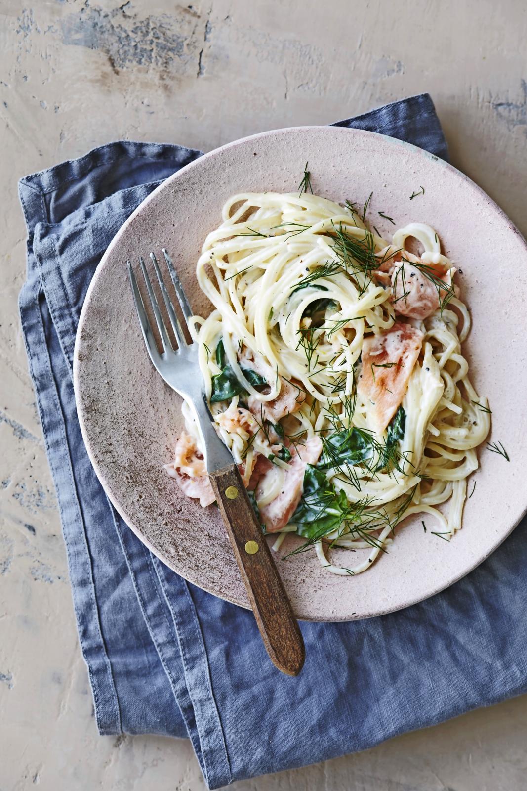 Nem og lækker aftensmad af pasta og laks på sart rosa tallerken. 