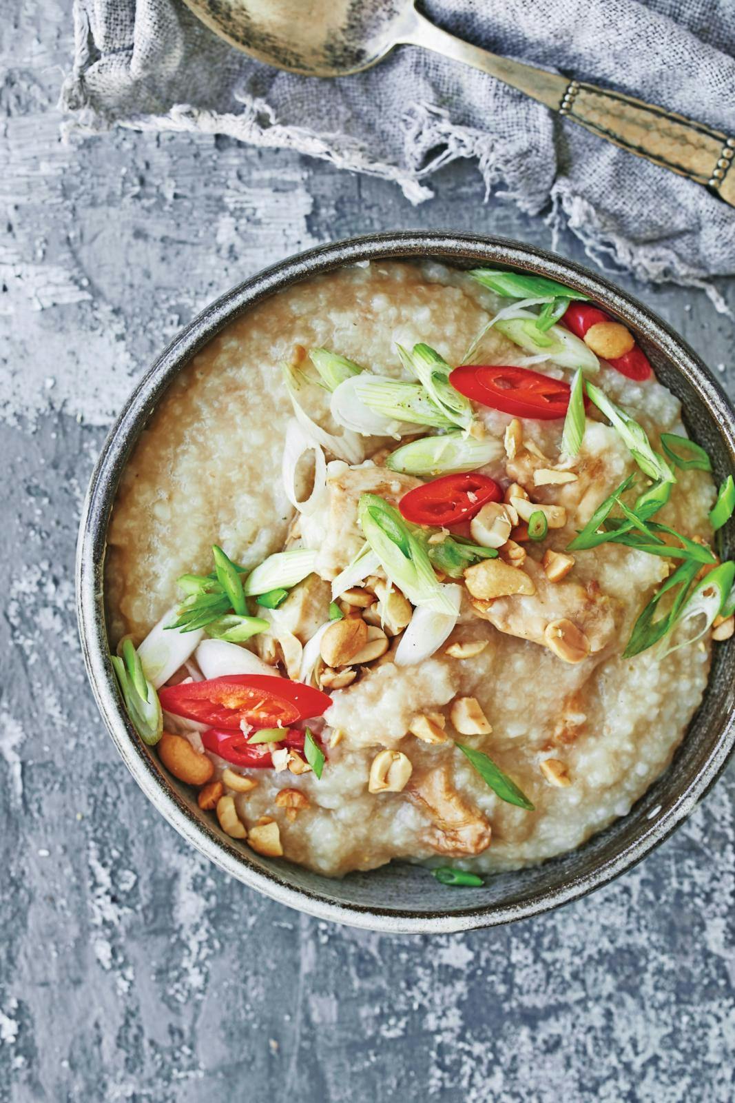Congee med soyastegt kylling og toppet med chili, forårsløg og peanuts