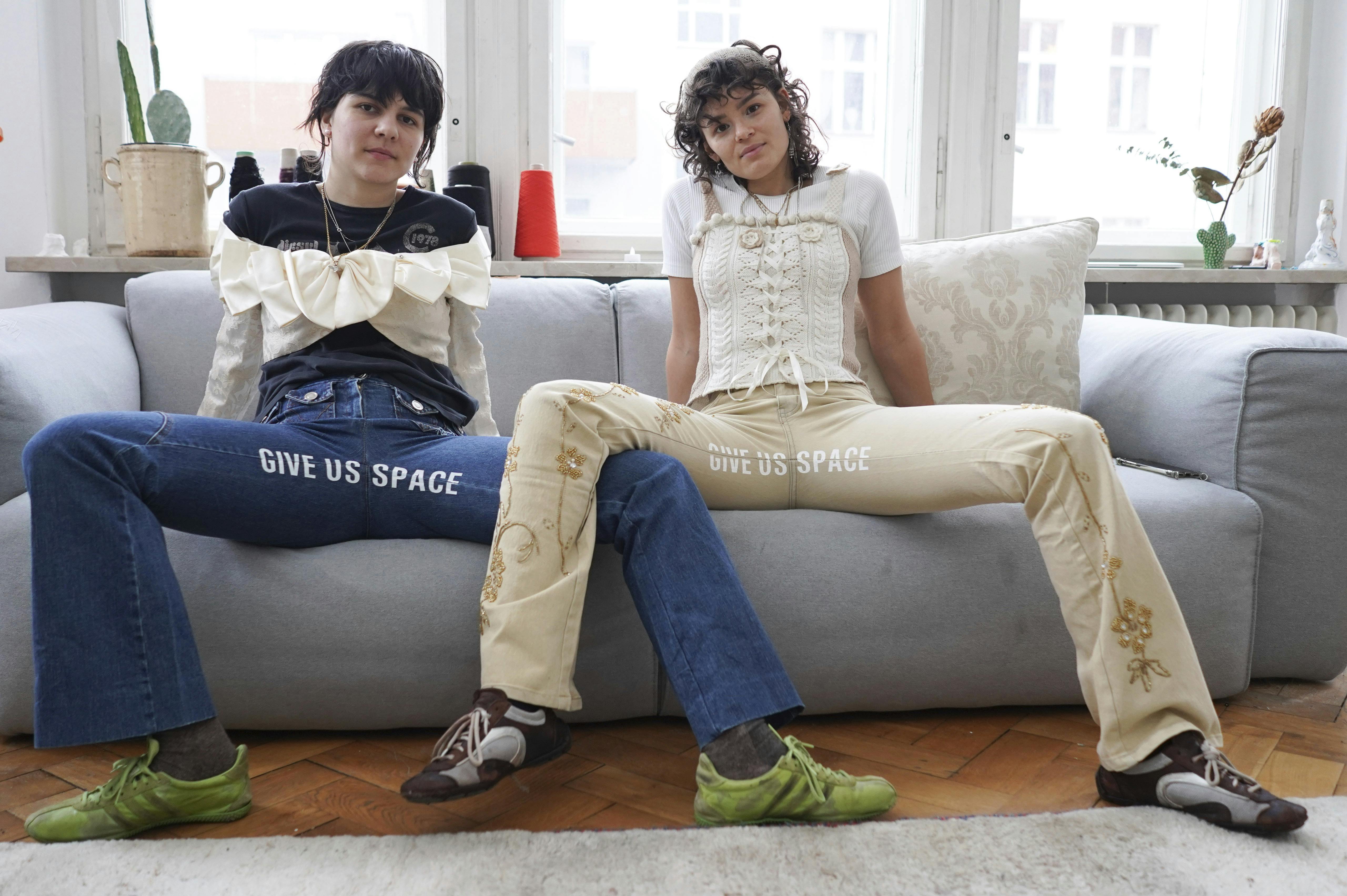 22 January 2021, Berlin: Designers Mina Bonakdar (l) and Elena Buscaino take on "manspreading" with slogans on the crotch of their pants and sit on a sofa. The "Riot Pant Project" makes a statement against spacey macho gestures on public transport. (to dpa-KORR.: "When men manspread - Berlin women make a statement") Photo by: J'rg Carstensen/picture-alliance/dpa/AP Images