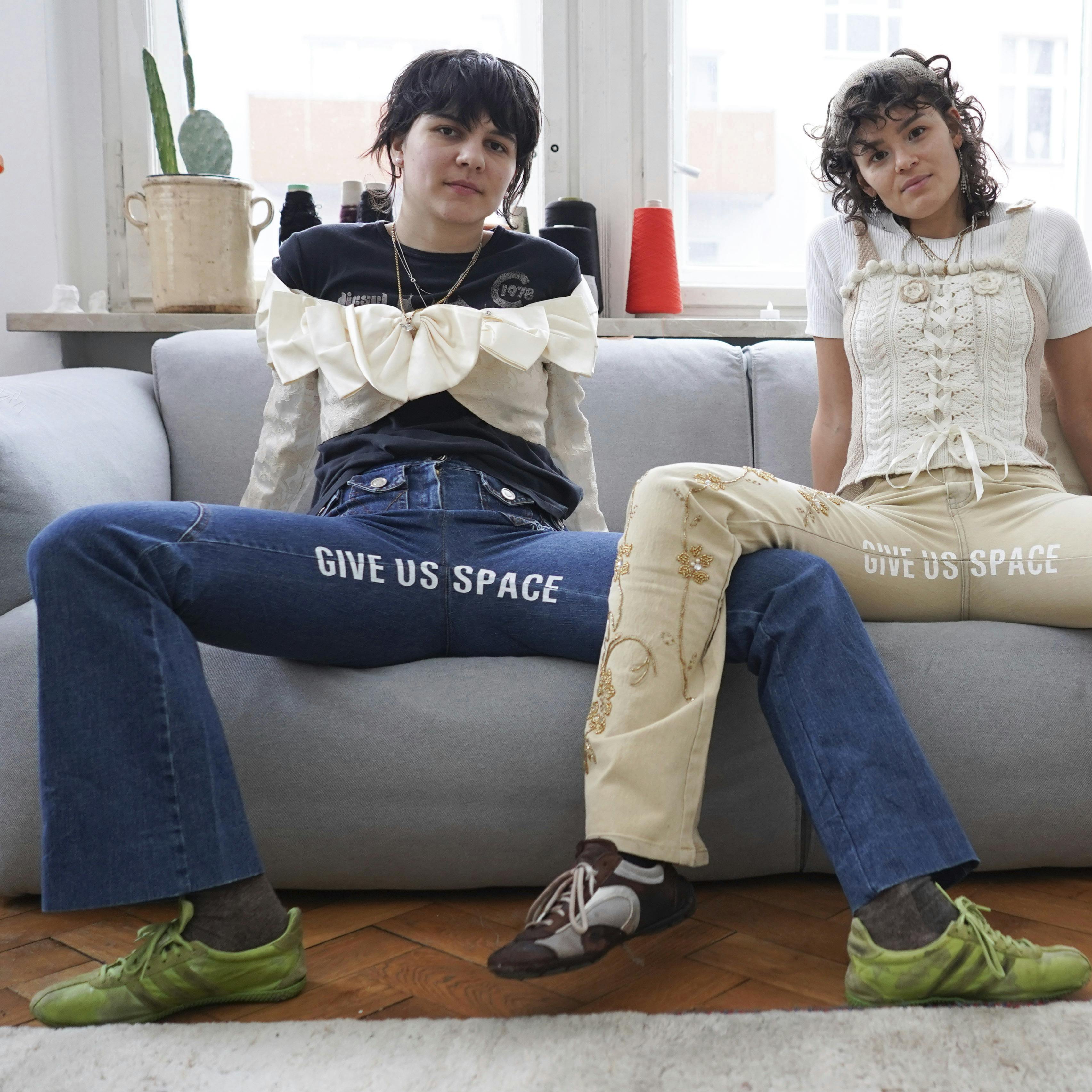 22 January 2021, Berlin: Designers Mina Bonakdar (l) and Elena Buscaino take on "manspreading" with slogans on the crotch of their pants and sit on a sofa. The "Riot Pant Project" makes a statement against spacey macho gestures on public transport. (to dpa-KORR.: "When men manspread - Berlin women make a statement") Photo by: J'rg Carstensen/picture-alliance/dpa/AP Images
