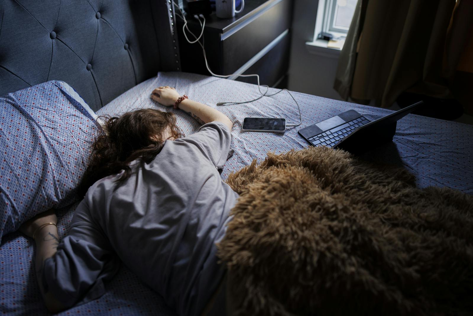 Bad sleeping habits of young woman in bed. Tired woman sleeping after restless night with gadgets