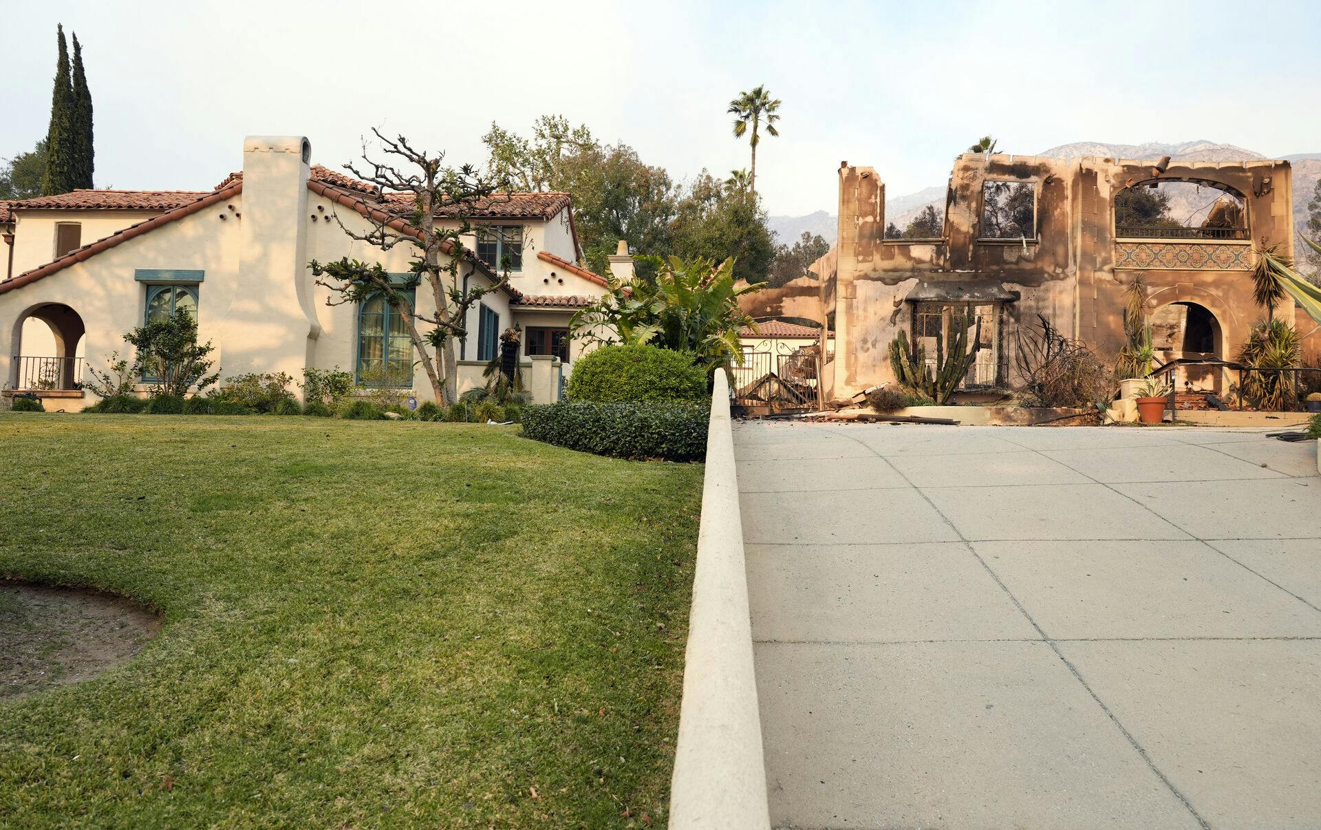 The front exterior of the Walsh House featured in the television series "Beverly Hills 90210, " left, stands undamaged next to a house charred by the Eaton Fire, Thursday, Jan. 9, 2025, in Altadena, Calif. (AP Photo/Chris Pizzello)