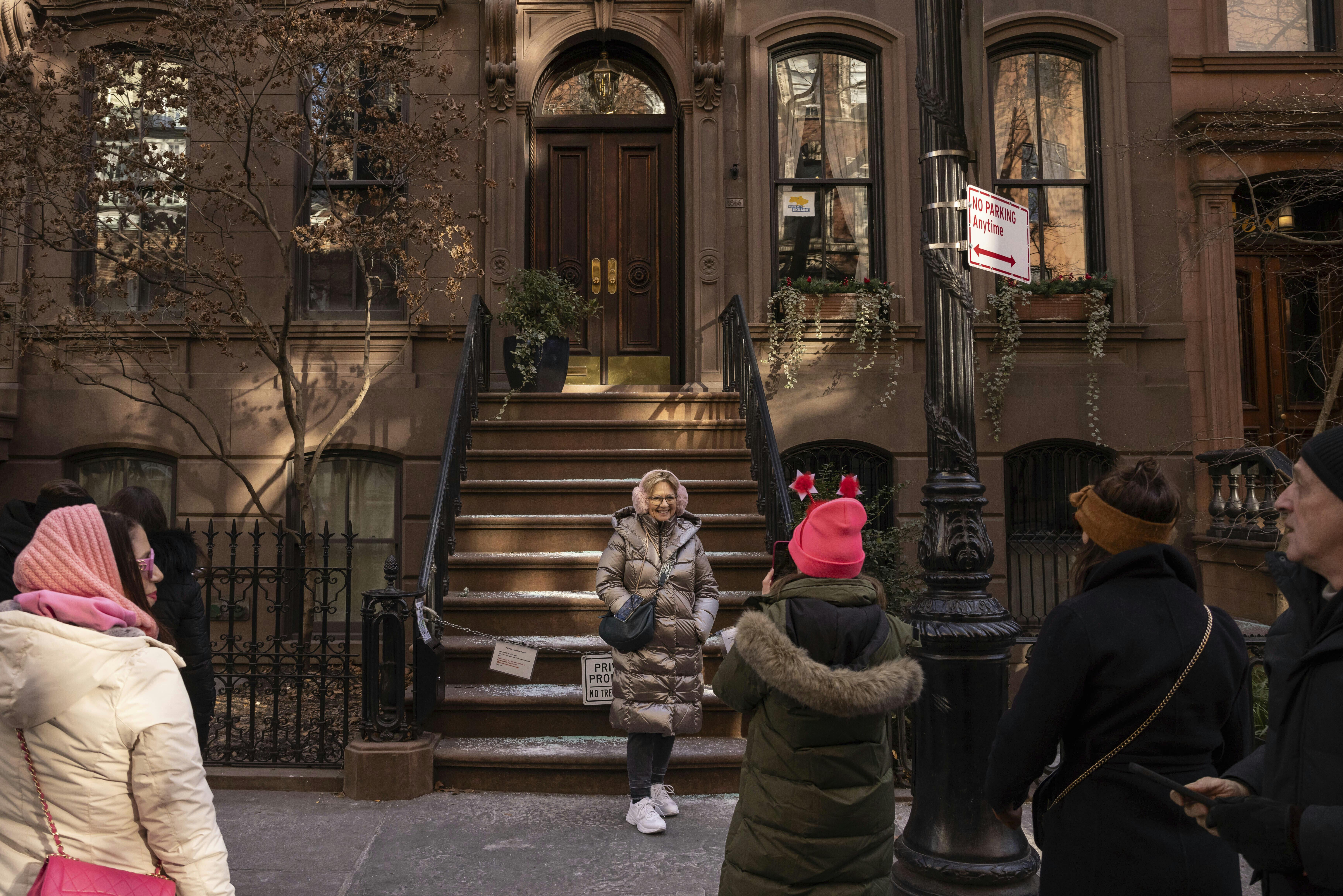 A person poses for a photo in front of the brownstone where Carrie Bradshaw lived in 'Sex and the City', in New York, Wednesday, Jan. 15, 2025. The city's Landmarks Preservation Commission approved an application for a metal gate for the front staircase of the Manhattan brownstone to keep away tourists who endlessly trespass and pose for pictures. (AP Photo/Yuki Iwamura)