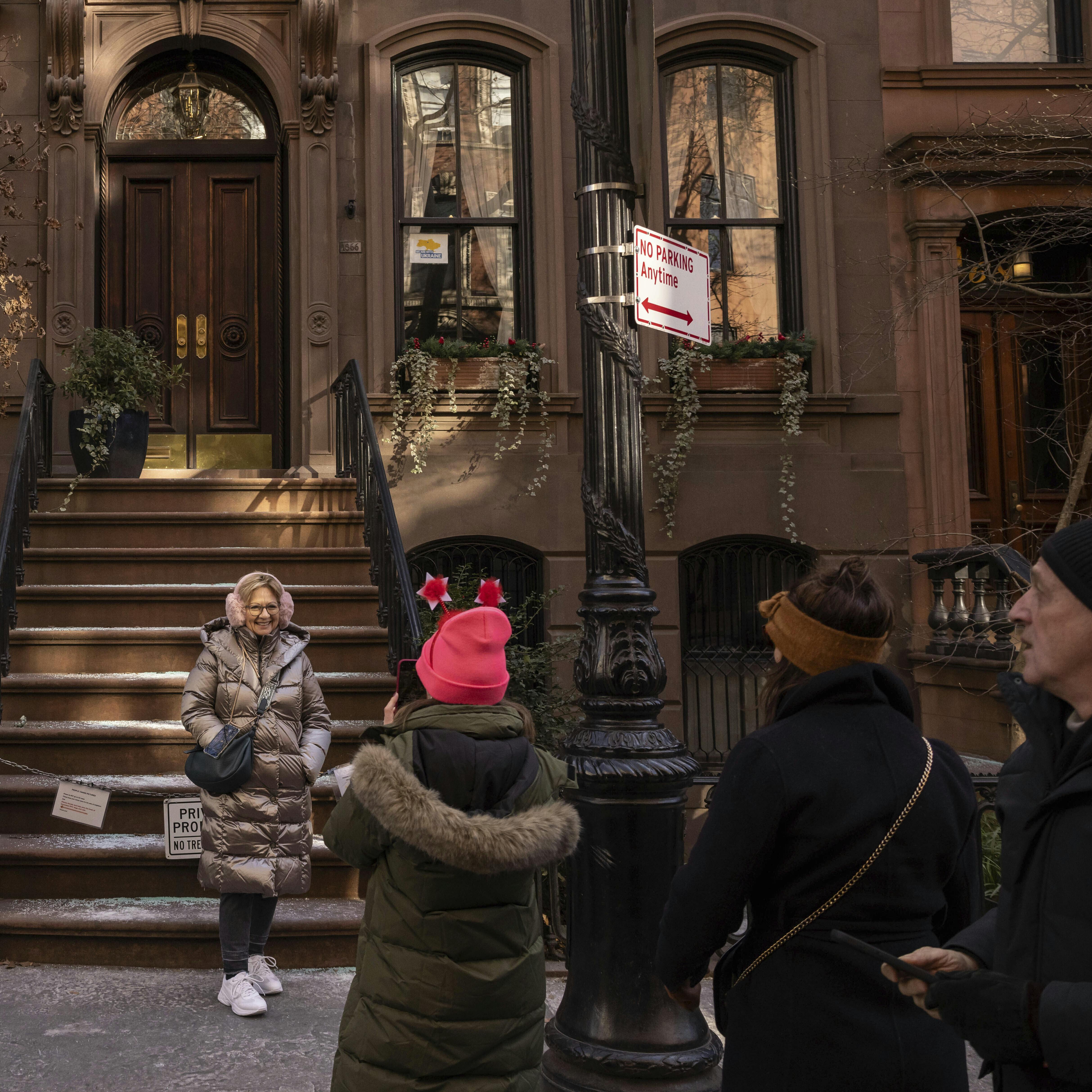 A person poses for a photo in front of the brownstone where Carrie Bradshaw lived in 'Sex and the City', in New York, Wednesday, Jan. 15, 2025. The city's Landmarks Preservation Commission approved an application for a metal gate for the front staircase of the Manhattan brownstone to keep away tourists who endlessly trespass and pose for pictures. (AP Photo/Yuki Iwamura)