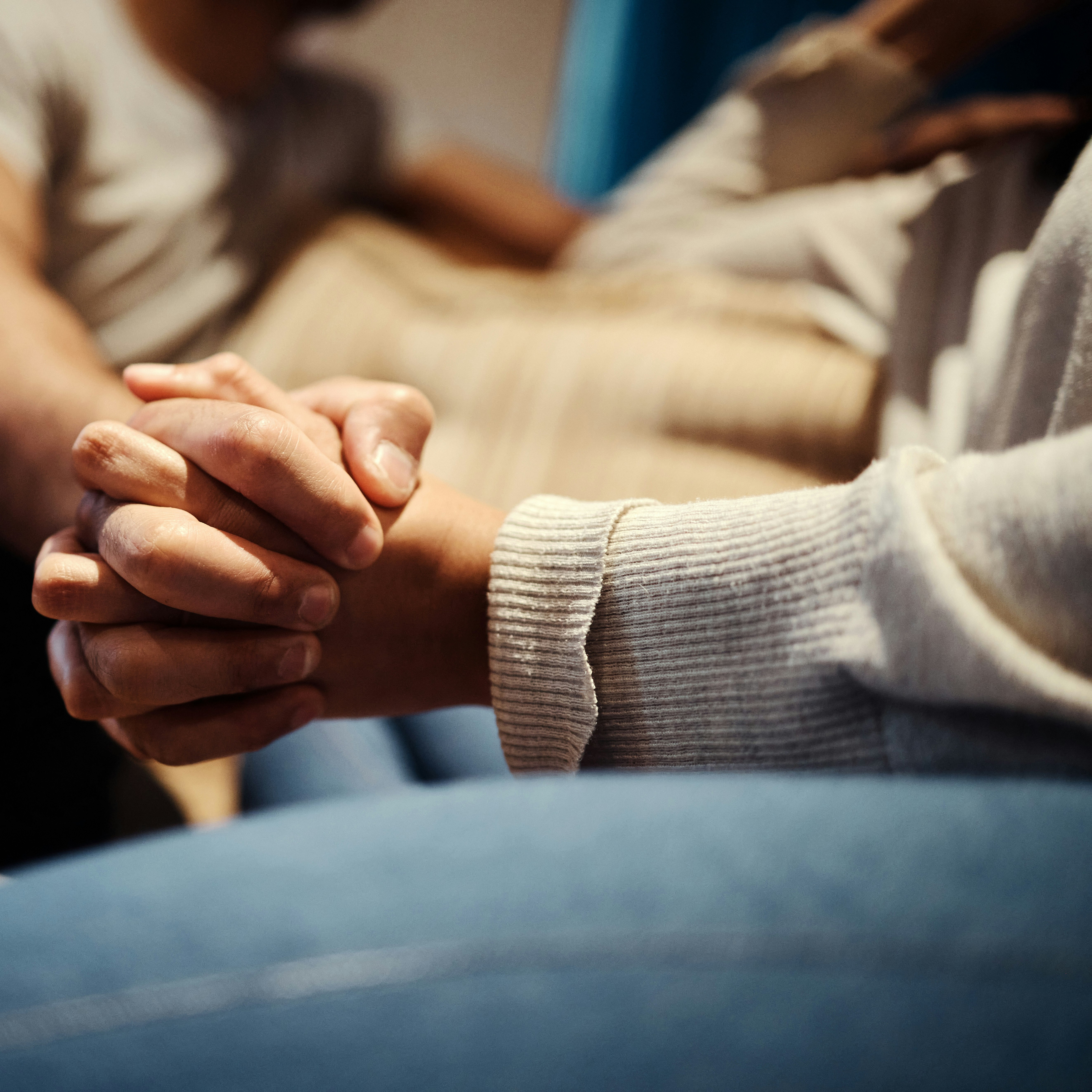 Holding hands, couple and love on couch for romance, home and support or empathy in marriage. People, trust and relax on sofa and connect on date in apartment, care and kindness in relationship.