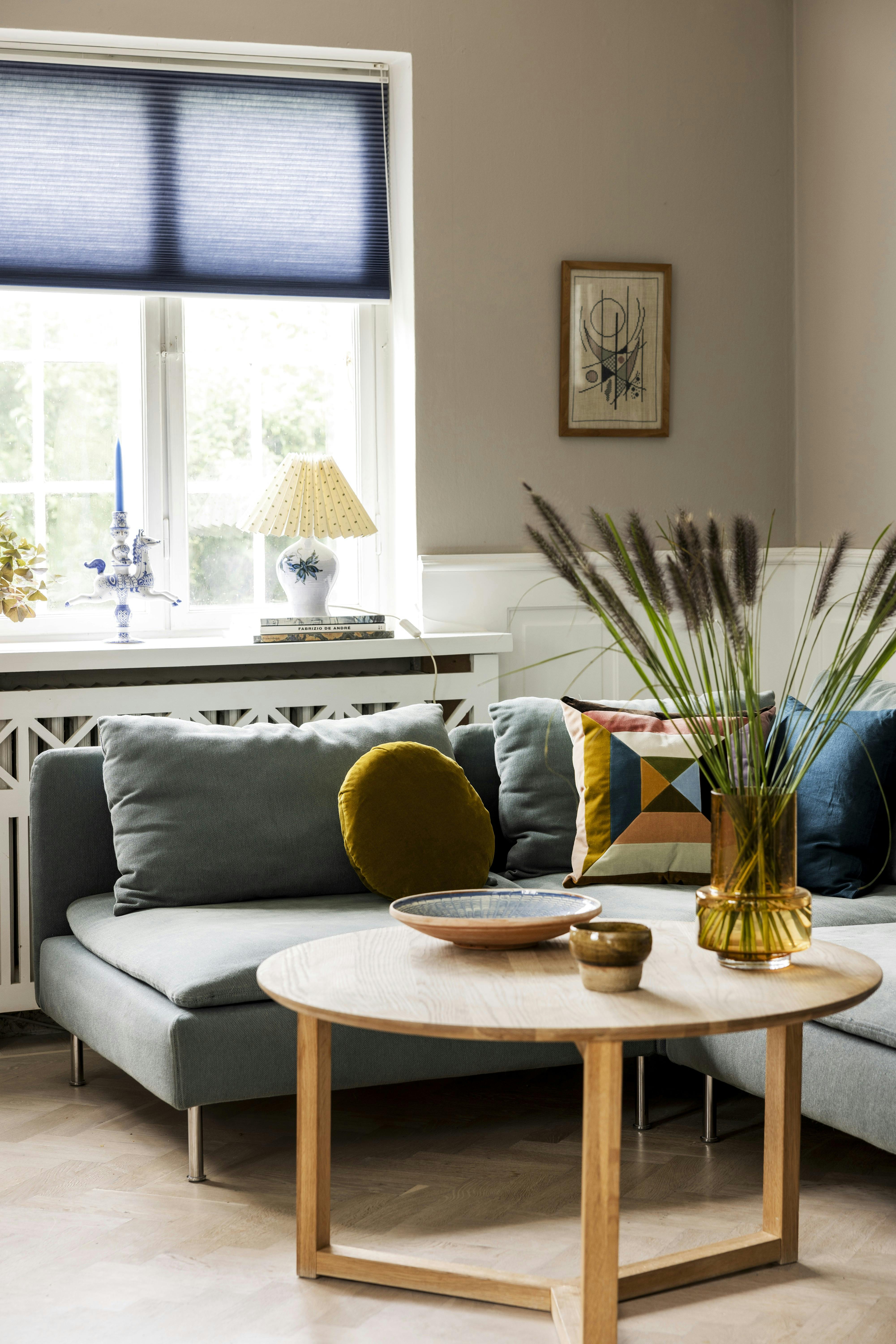Puderne er fra Roomers & Woodbox, gardin fra Faber, sofabord fra Møbellageret.dk, vasen er fra Ro Collection, og fadet fra De Fire Årstider.