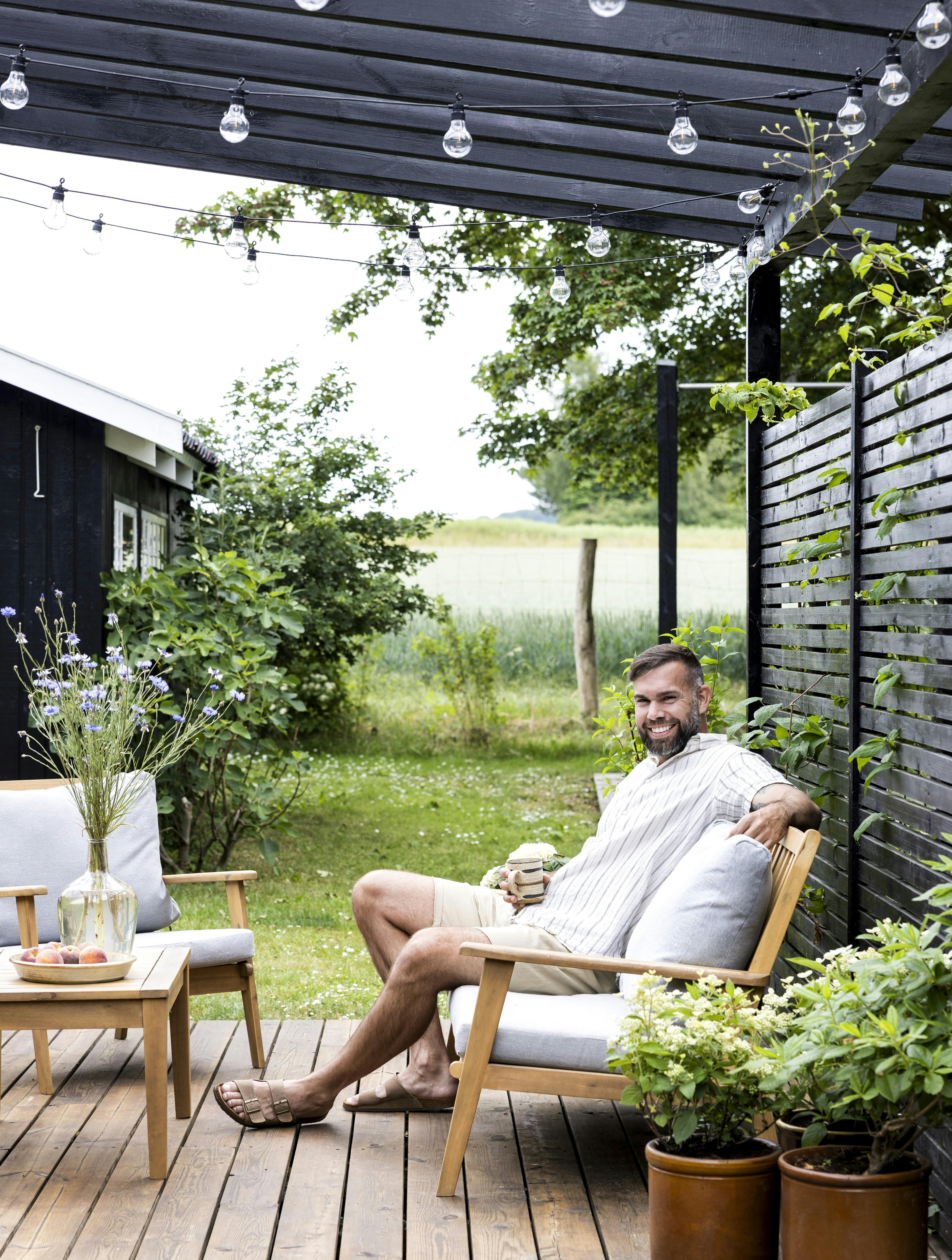 Casper Aagaard nyder en pause på terrassen, hvor sommerhuslivet giver plads til både ro, nærvær og små projekter.