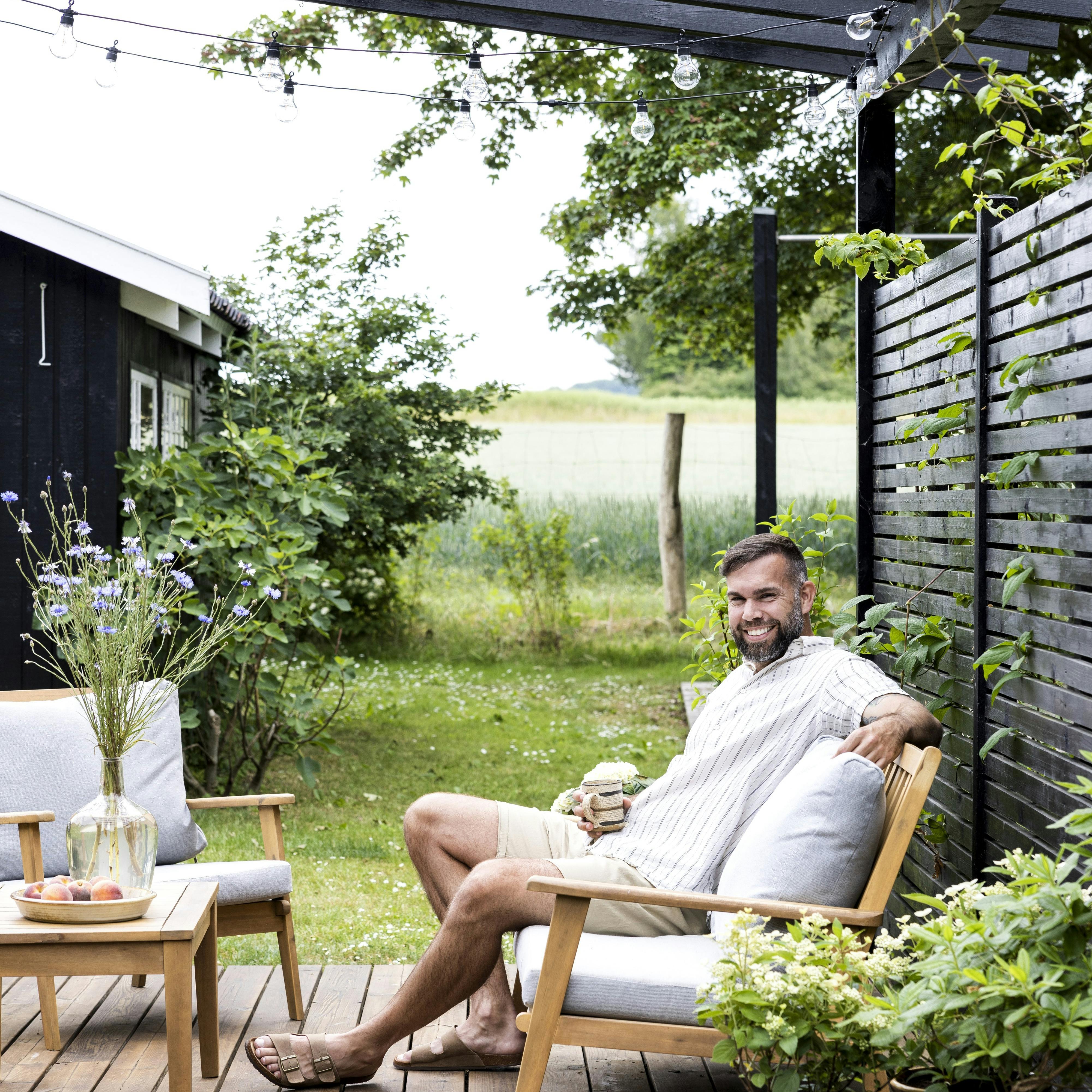 Casper Aagaard nyder en pause på terrassen, hvor sommerhuslivet giver plads til både ro, nærvær og små projekter.