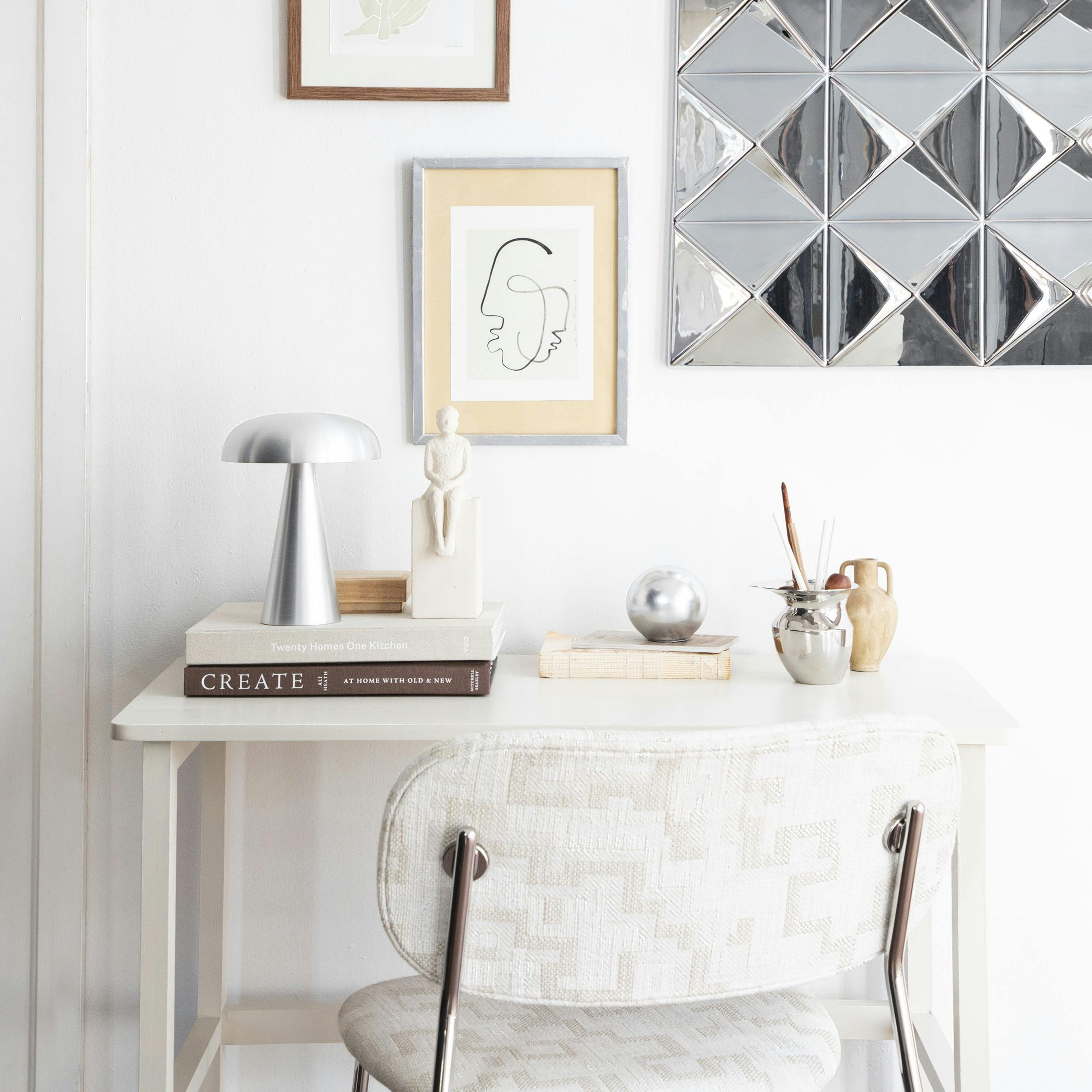 Lille ramme af træ og kunstkort fra Poster & Frame, stål-dekoration til væg og stol med kromben fra Verpan, bordlampe fra &Tradition, gipsfigur fra Kähler, mini-vase fra Ferm Living, sølvkande fra Audo Copenhagen, trææske fra Sakura Copenhagen og skrivebord fra Søstrene Grene.
