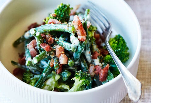 Broccolisalat med bønner og bacon i hvid skål 