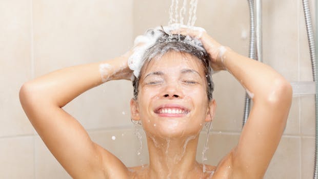 Kvinde, der vasker dit hår under bruseren