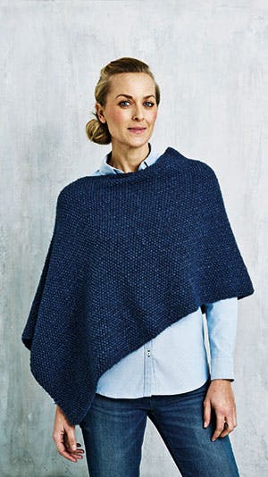 Kvinde i mørkeblå strikket poncho - gratis strikkeopskrift