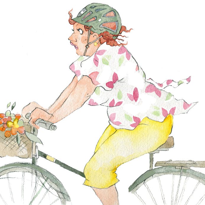 Kvinde cykler med hjelm på cykel med cykelkurv
