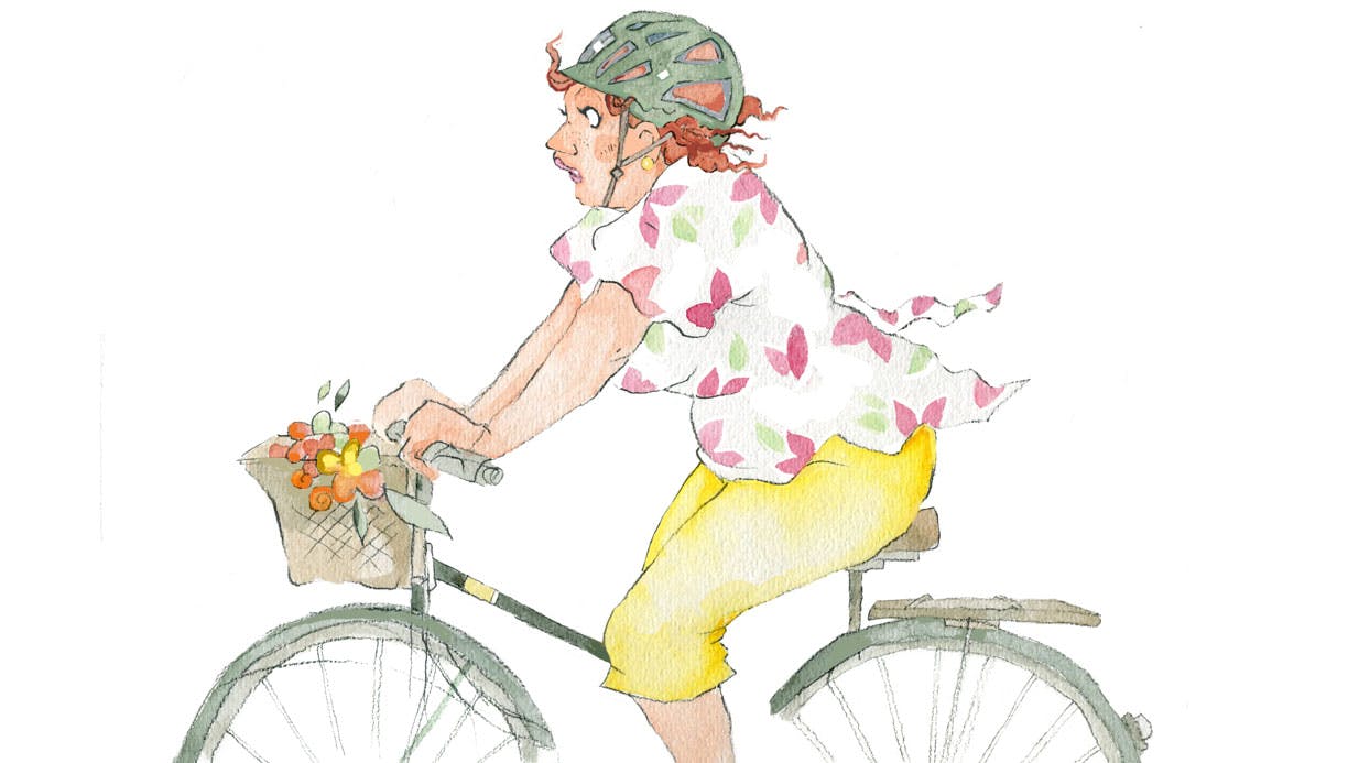 Kvinde cykler med hjelm på cykel med cykelkurv