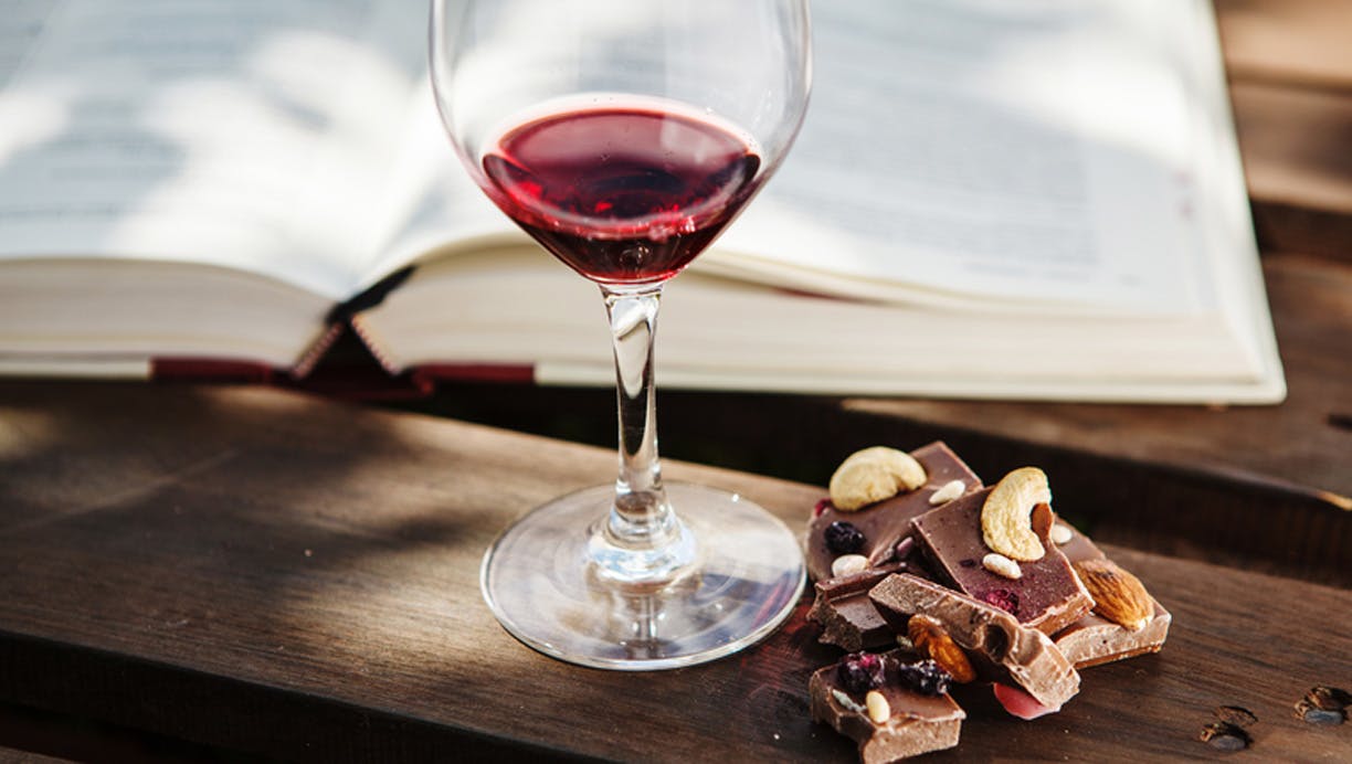 Rødvin, chokolade og nødder på et bord